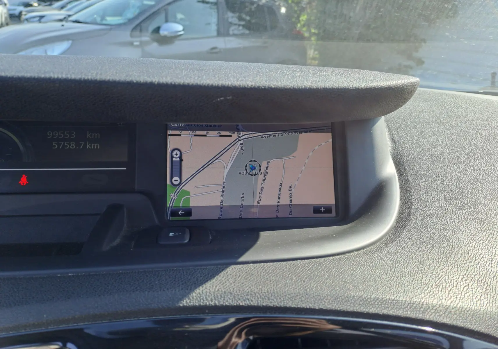 Vue intérieure du tableau de bord du Renault Scenic III gris de 2016, avec écran de navigation et compteur kilométrique visible.
