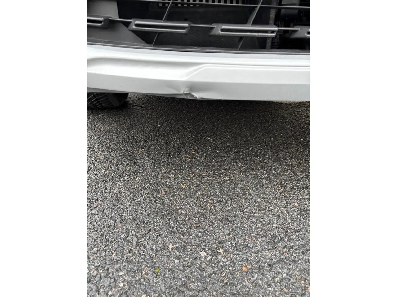 Gros plan sur le pare-chocs avant blanc du Renault Captur 2024, avec une bosse visible au centre.