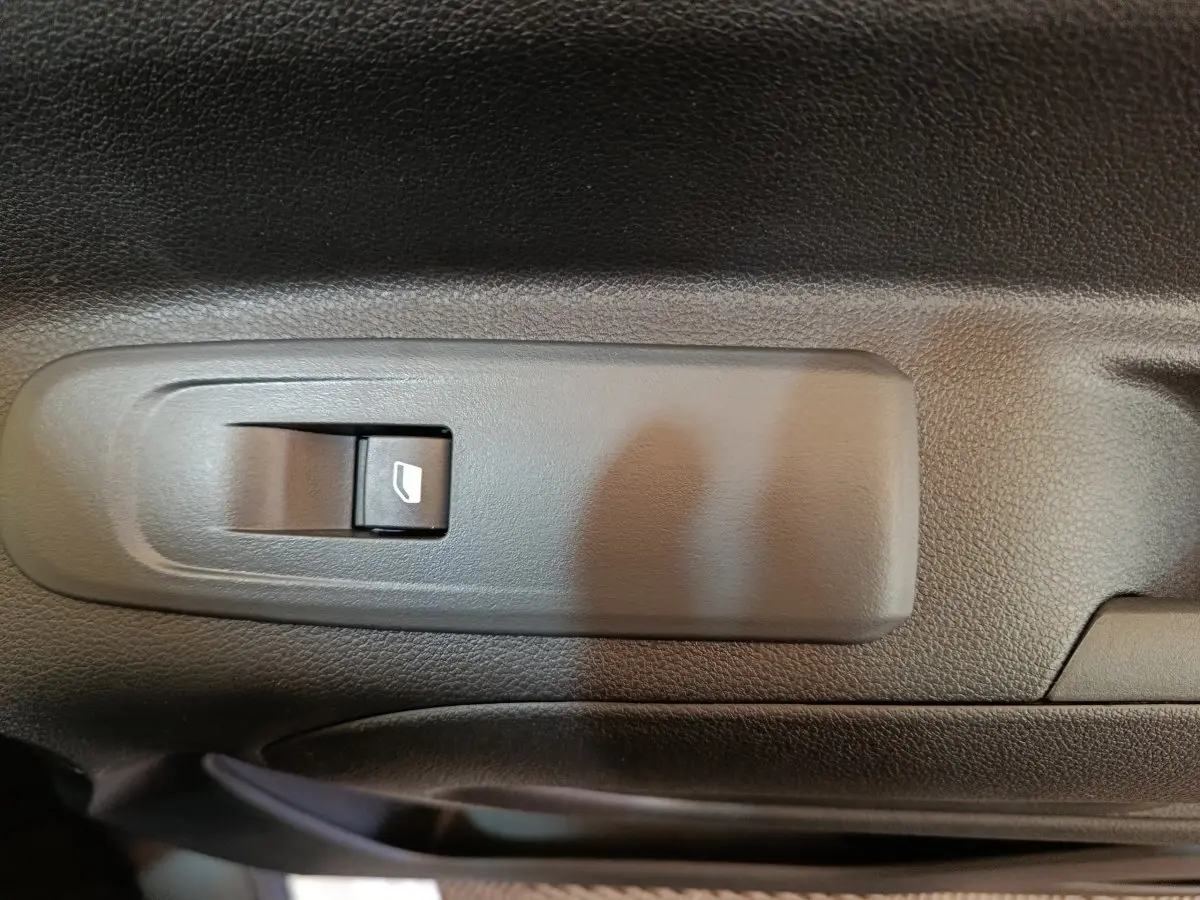 Gros plan sur le bouton de commande de vitre électrique sur la porte intérieure noire du Peugeot Partner blanc 2025.
