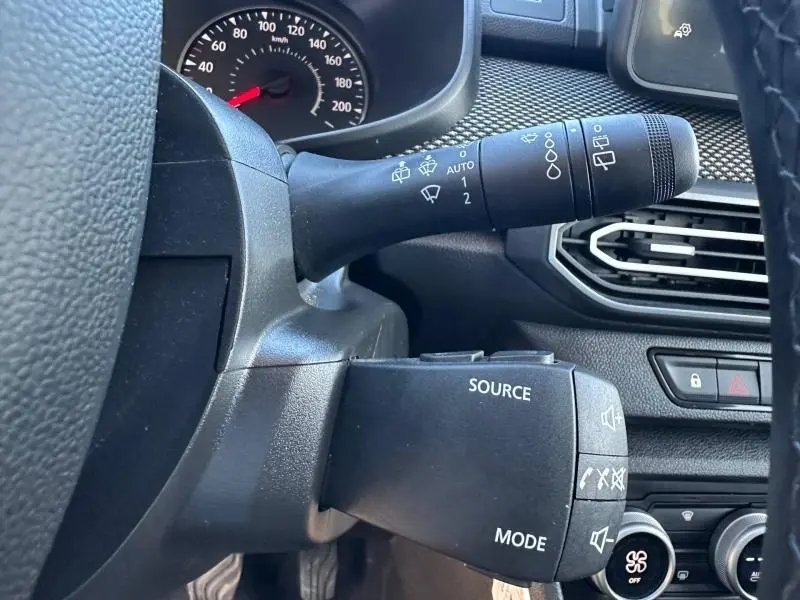 Gros plan sur la commande multifonction côté gauche du volant du Dacia Jogger gris Schiste métallisé, tableau de bord en arrière-plan.