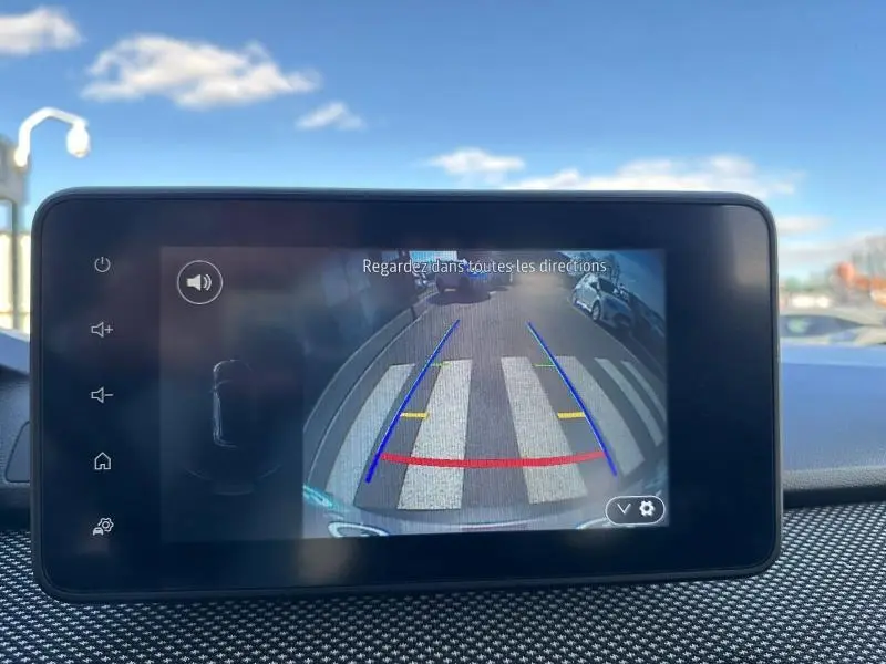 Vue arrière via caméra de recul du Dacia Jogger gris schiste métallisé, montrant un passage piéton et des lignes de guidage colorées.