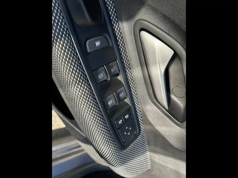 Détail des commandes de lève-vitres et poignée intérieure côté conducteur du Dacia Jogger gris schiste métallisé.