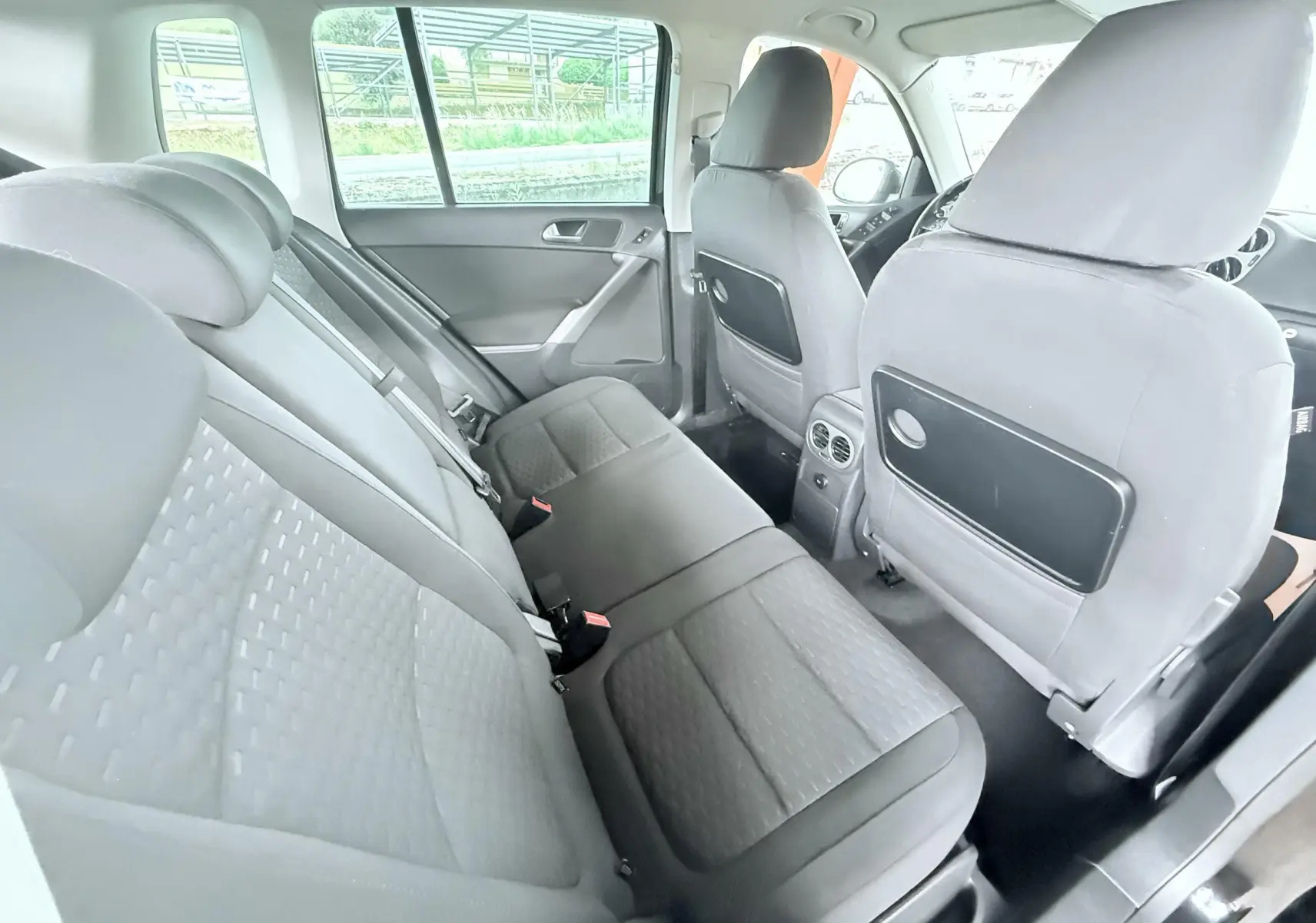Vue intérieure arrière du Volkswagen Tiguan 2007 noir, montrant les sièges arrière en tissu gris et les dossiers avant avec rangements.