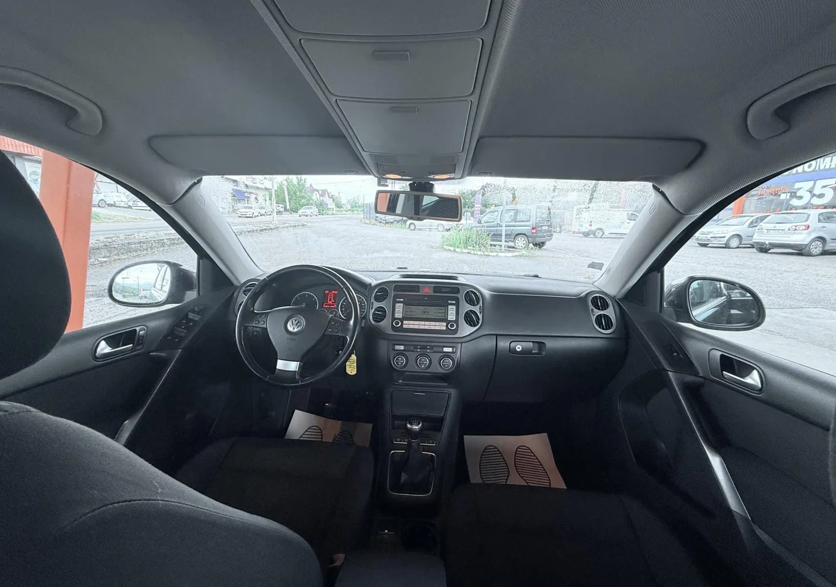 Vue intérieure avant du Volkswagen Tiguan 2007, tableau de bord et volant noirs avec boîte manuelle visible.