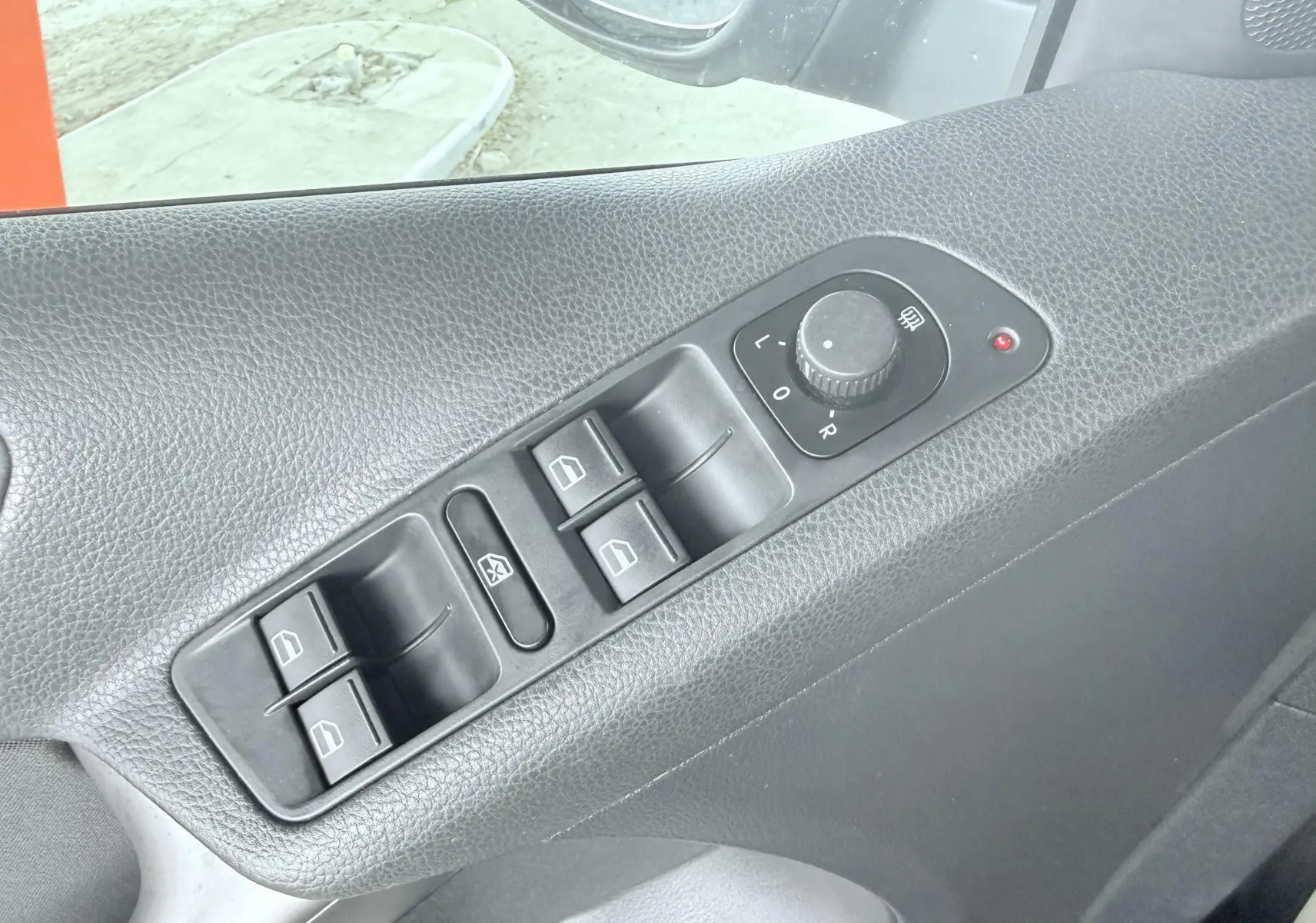 Gros plan sur les commandes de lève-vitres et réglage des rétroviseurs côté conducteur d’un Volkswagen Tiguan noir de 2007.