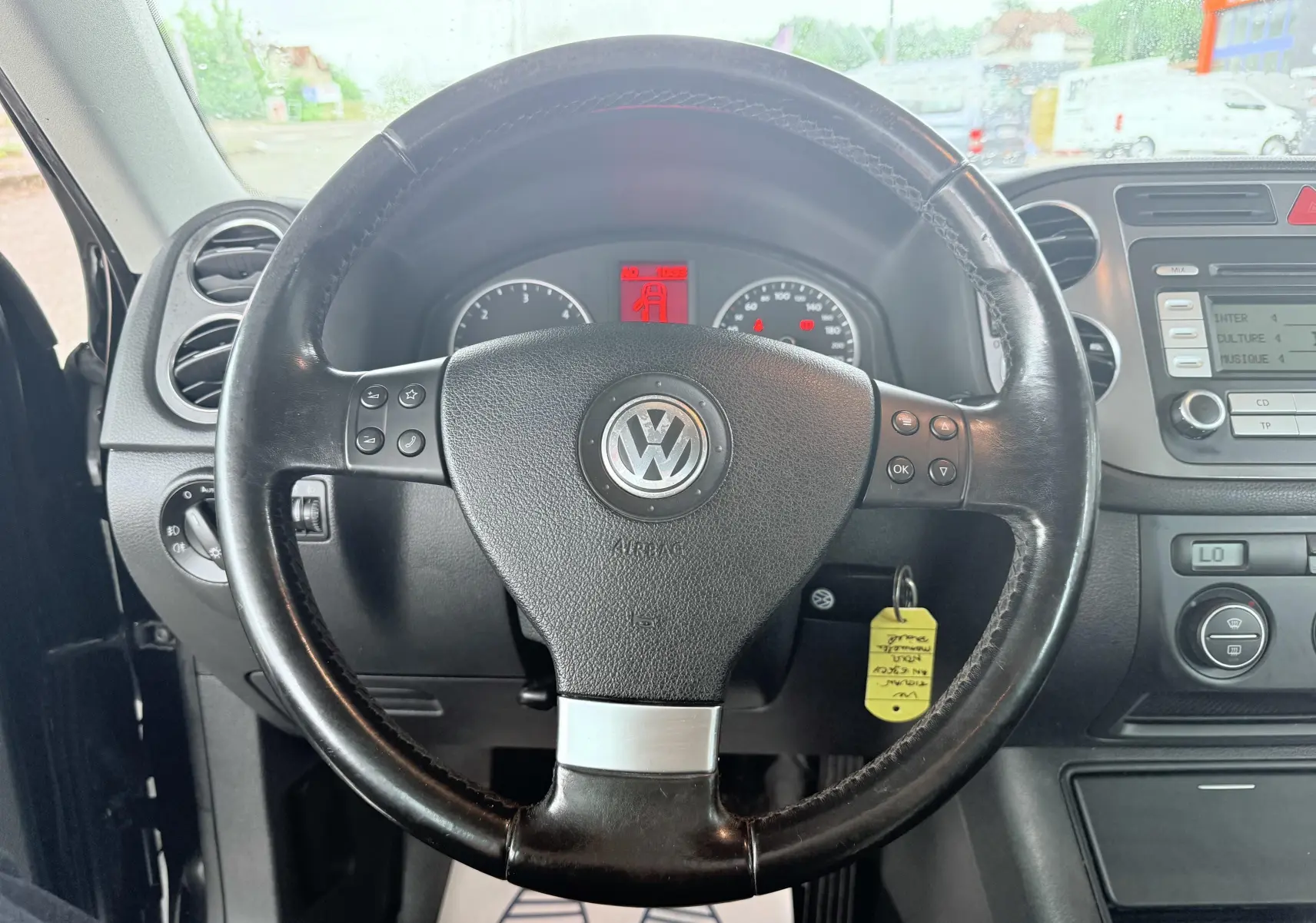 Vue intérieure centrée sur le volant noir en cuir du Volkswagen Tiguan 2007 avec tableau de bord et commandes visibles.