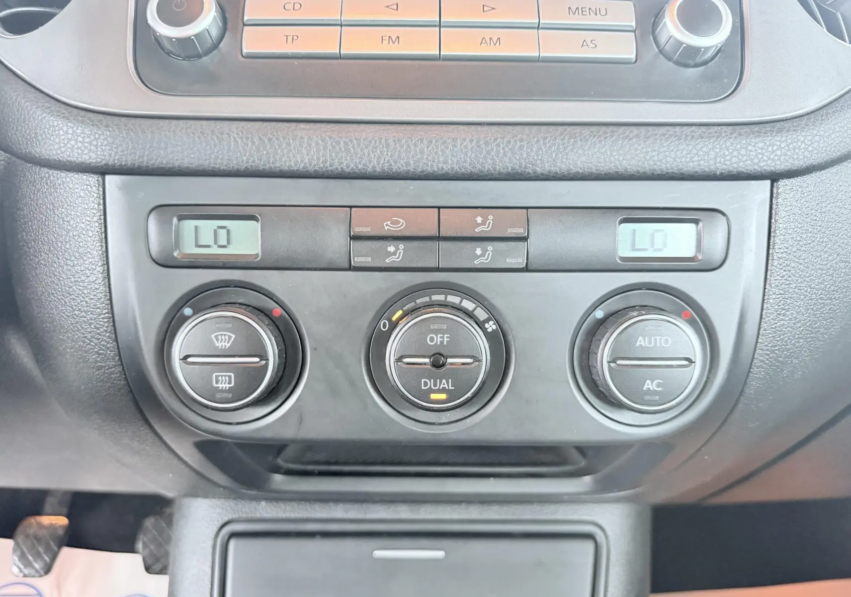 Vue rapprochée de la console centrale du Volkswagen Tiguan 2007, montrant les commandes de climatisation automatique et radio.