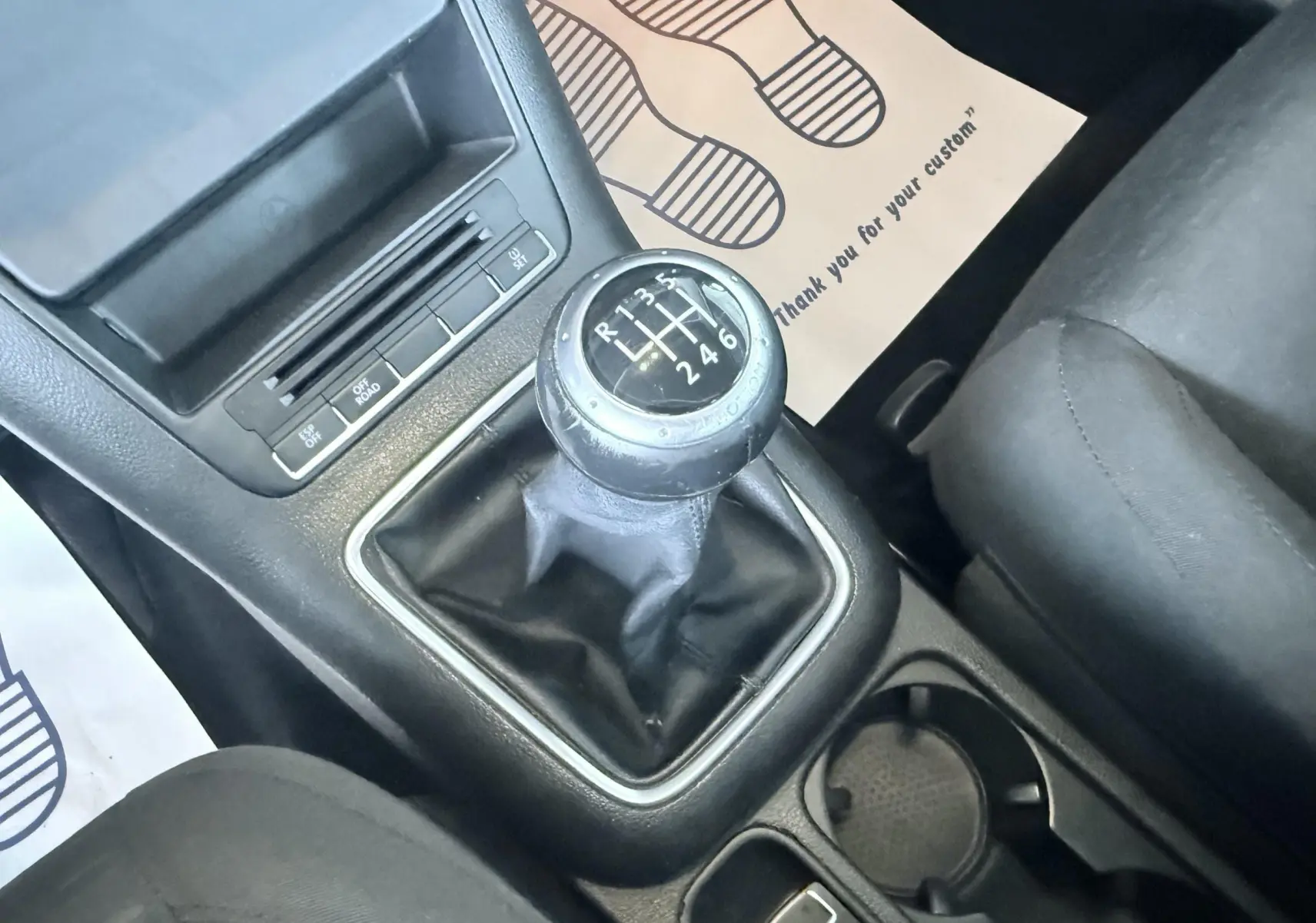 Gros plan sur le levier de vitesses manuel noir du Volkswagen Tiguan 2.0 TDI, avec console centrale et siège tissu noir visibles.