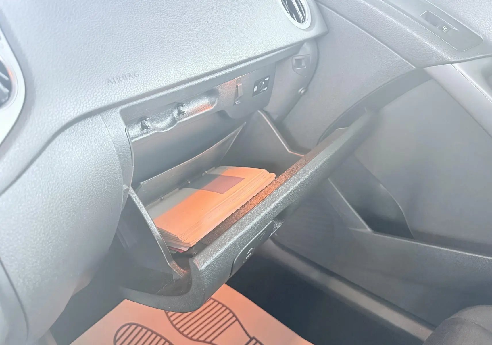 Vue intérieure du Volkswagen Tiguan 2007 montrant la boîte à gants ouverte côté passager avec des documents à l'intérieur.