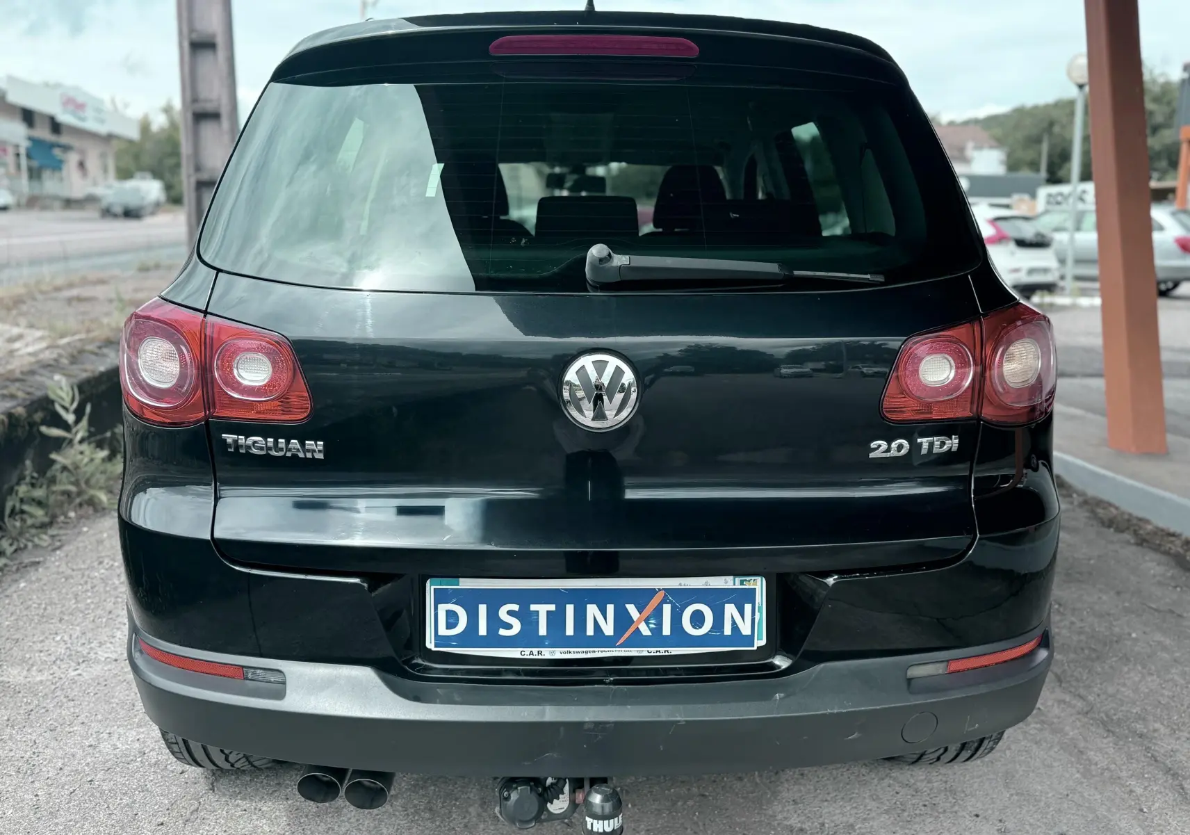 Vue arrière d’un Volkswagen Tiguan noir 2.0 TDI avec attelage et plaque Distinxion visible.