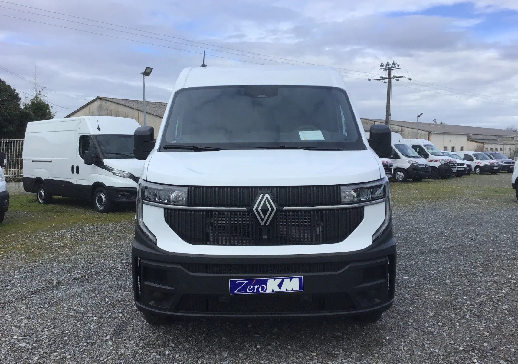 Vue frontale d’un Renault Master blanc 2026 avec calandre noire et logo Renault bien visible sur un parking.