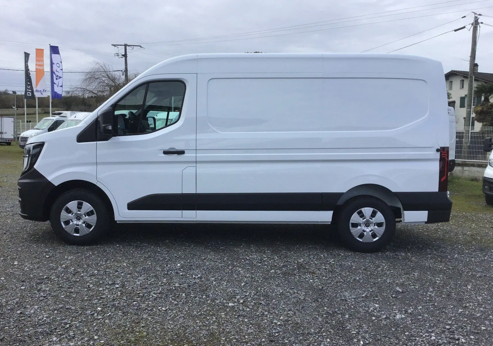 Vue latérale gauche d’un Renault Master blanc L2H2, fourgon utilitaire avec protections noires sur les bas de caisse.