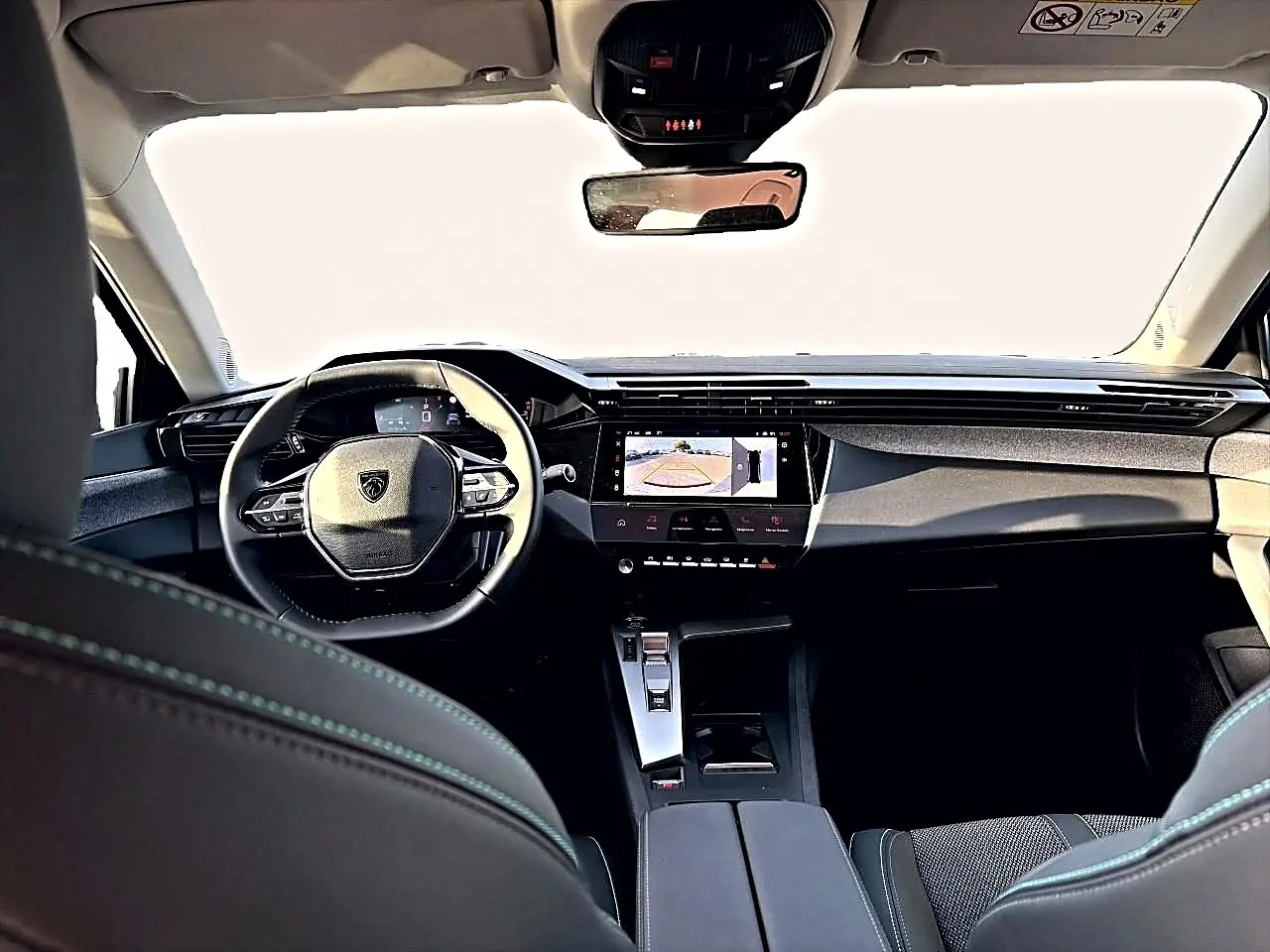 Vue intérieure avant du Peugeot 408 noir 2025, avec tableau de bord moderne et écran tactile affichant la caméra de recul.
