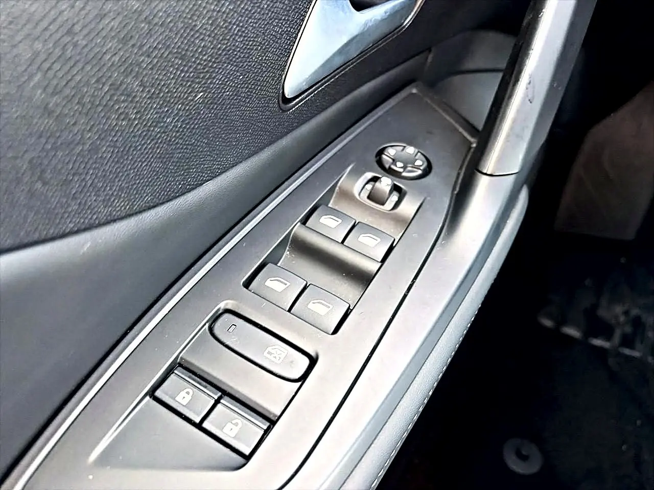 Gros plan sur les commandes des vitres et rétroviseurs côté gauche d’une Peugeot 408 noire, version Hybrid 145 allure 2025.