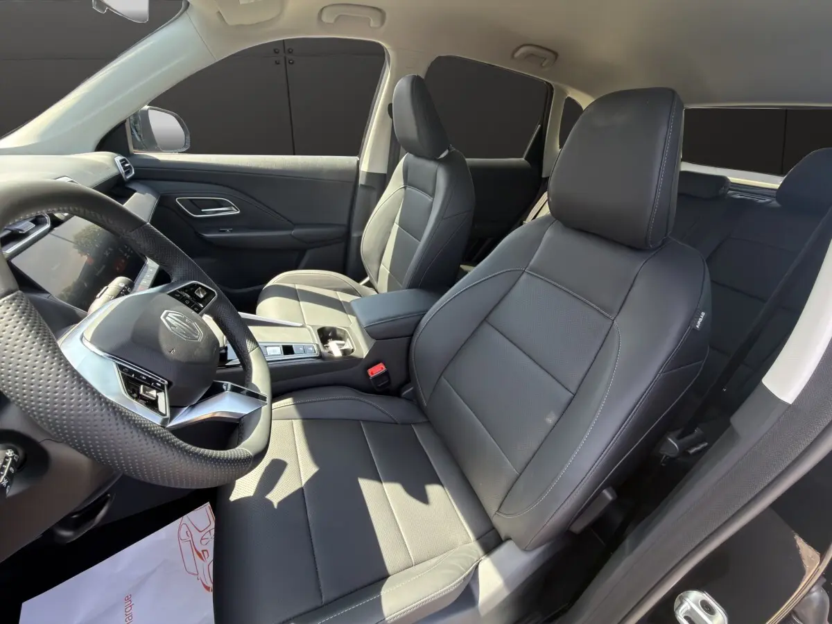 Vue intérieure côté conducteur du MG ZS noir 2026, sièges en cuir noir et volant multifonctions avec logo MG visible.