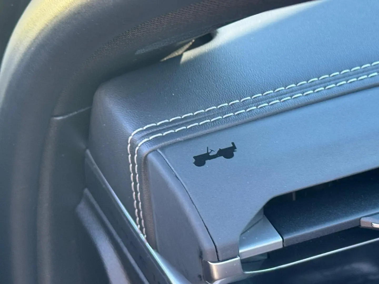 Détail de l'accoudoir central en cuir noir avec surpiqûres blanches et logo Jeep en relief sur un Compass Vulcano 2026.