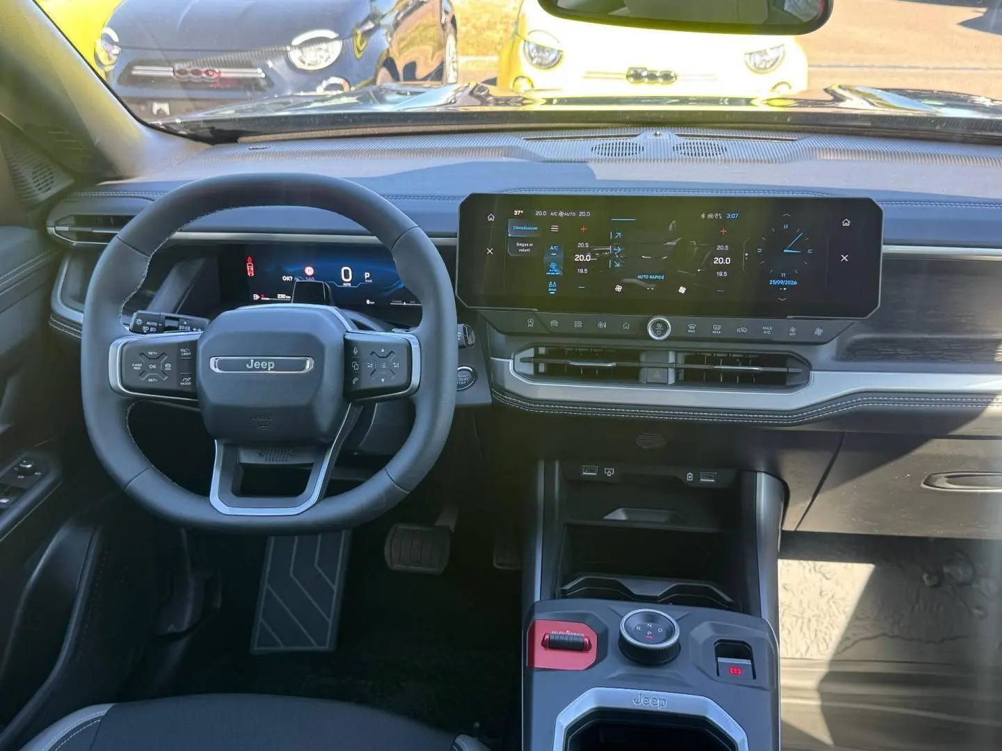 Vue intérieure avant du tableau de bord et volant Jeep Compass 2026 avec écran tactile large et commandes au volant.