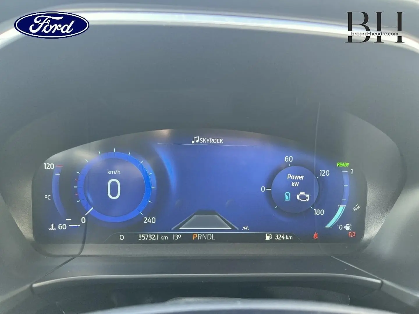 Vue rapprochée du tableau de bord numérique du Ford Kuga 2023, affichage bleu avec compteur km/h et indicateurs hybrides.