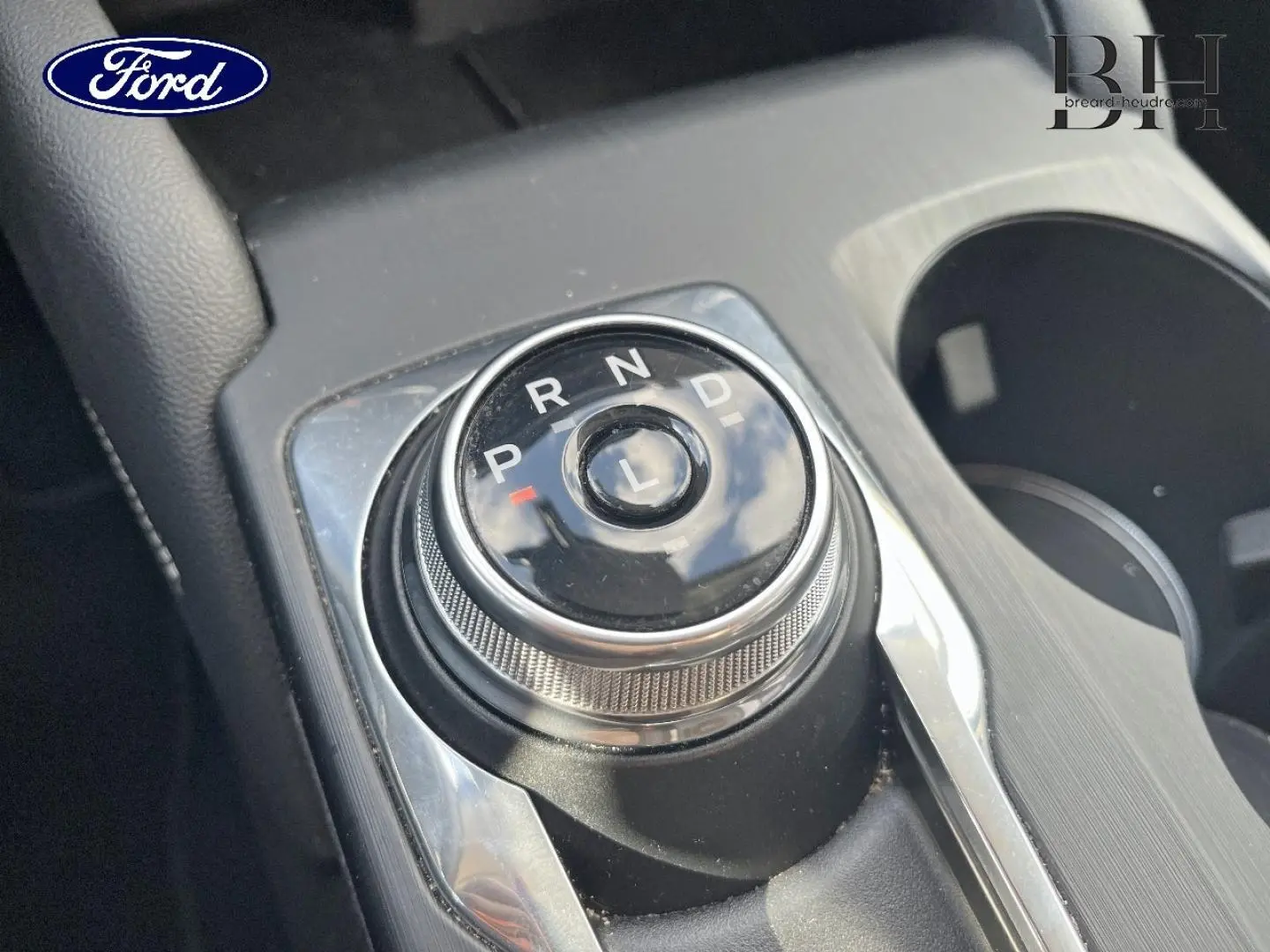 Gros plan sur la molette de sélection de la boîte automatique du Ford Kuga noir Agate, avec porte-gobelets à droite.
