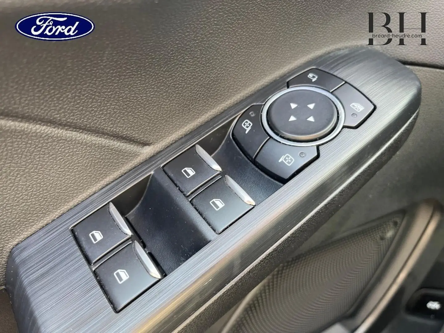 Gros plan sur les commandes de lève-vitres et réglages des rétroviseurs côté conducteur du Ford Kuga 2023 noir Agate.