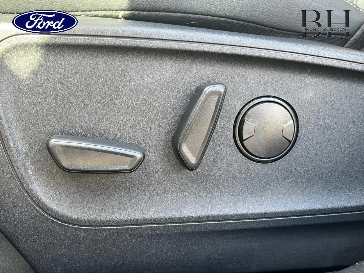 Détail des commandes de réglage électrique du siège côté gauche d’un Ford Kuga noir Agate Métallisée 2023.