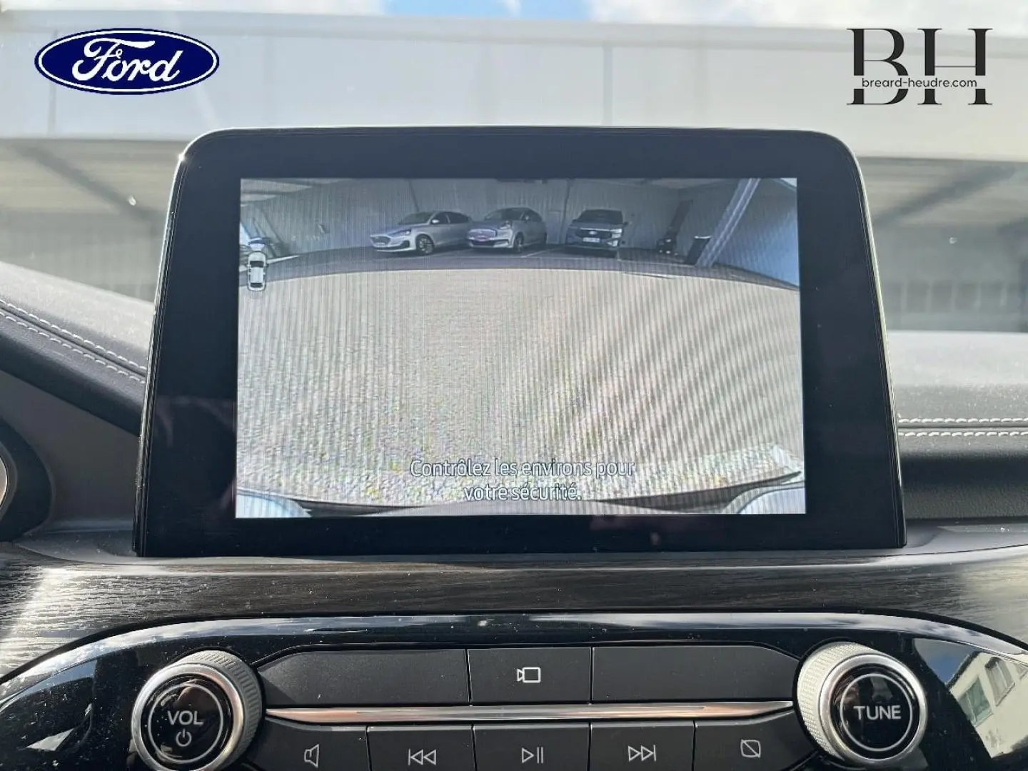 Écran tactile intérieur montrant la caméra de recul du Ford Kuga noir Agate, tableau de bord moderne avec commandes audio.