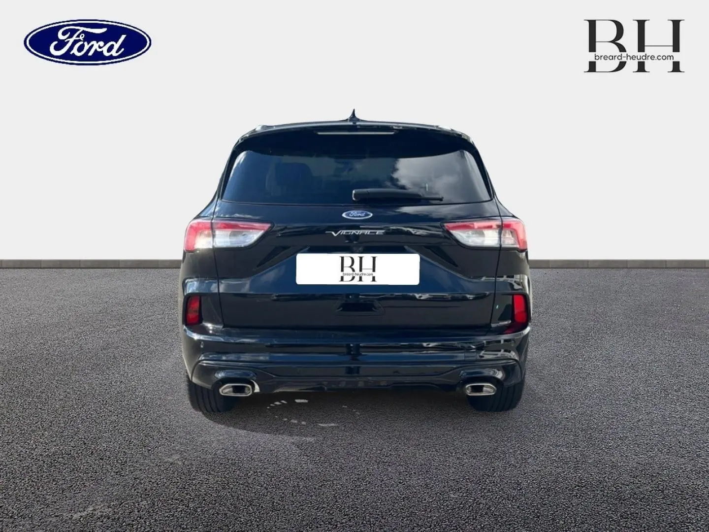 Vue arrière d'un Ford Kuga Vignale 2023 noir Agate métallisé avec double sortie d'échappement et lunette arrière surteintée.