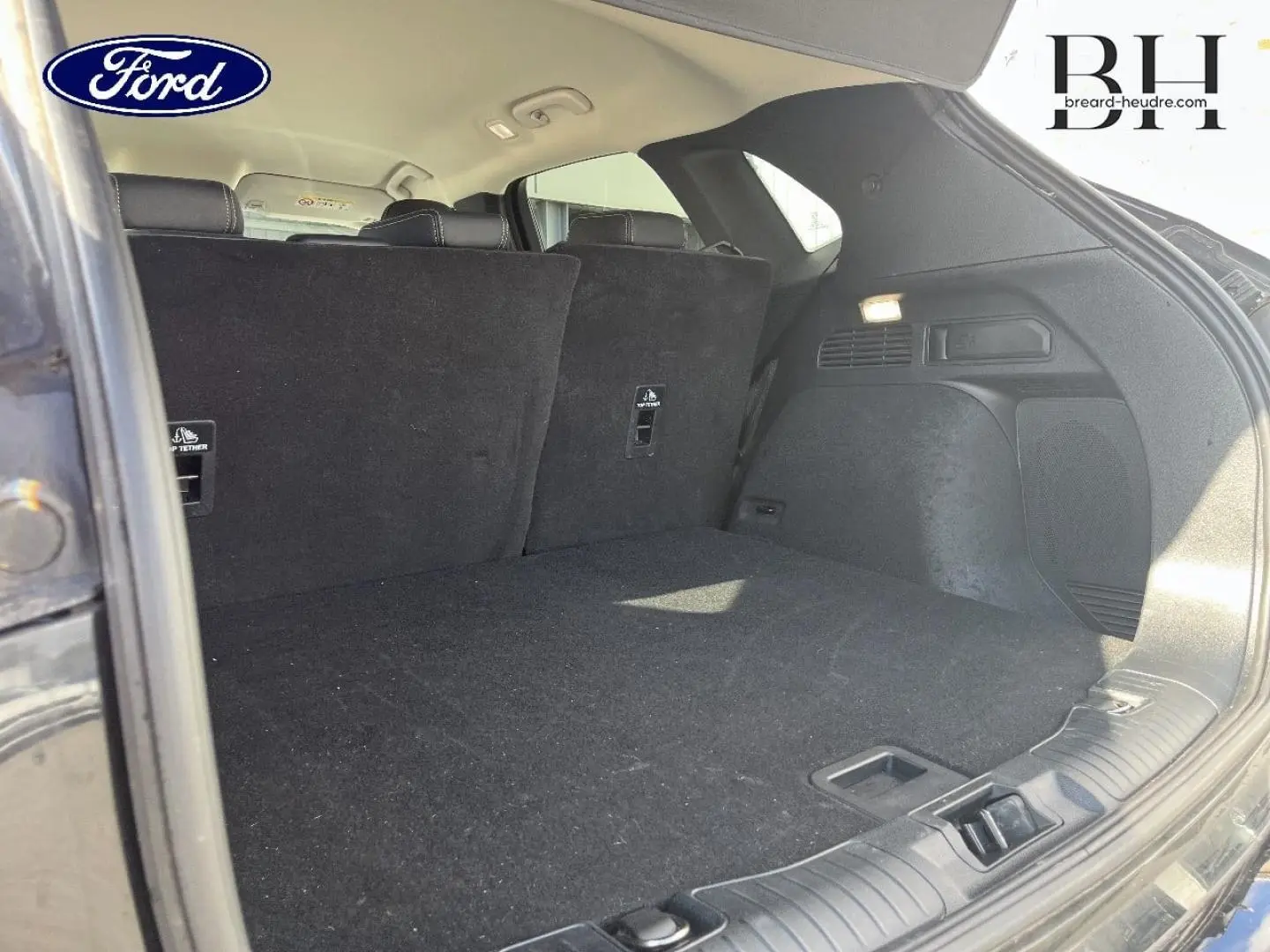 Coffre ouvert vu de l'arrière droit du Ford Kuga noir Agate Métallisée avec banquette arrière relevée.