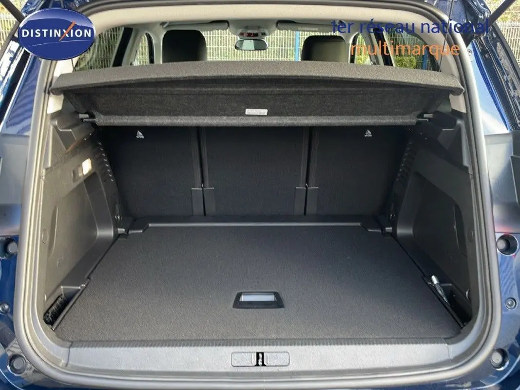 Coffre ouvert d'un Citroën C5 Aircross bleu Eclipse Metal, vue arrière montrant l'espace de chargement et la tablette cache-bagages.