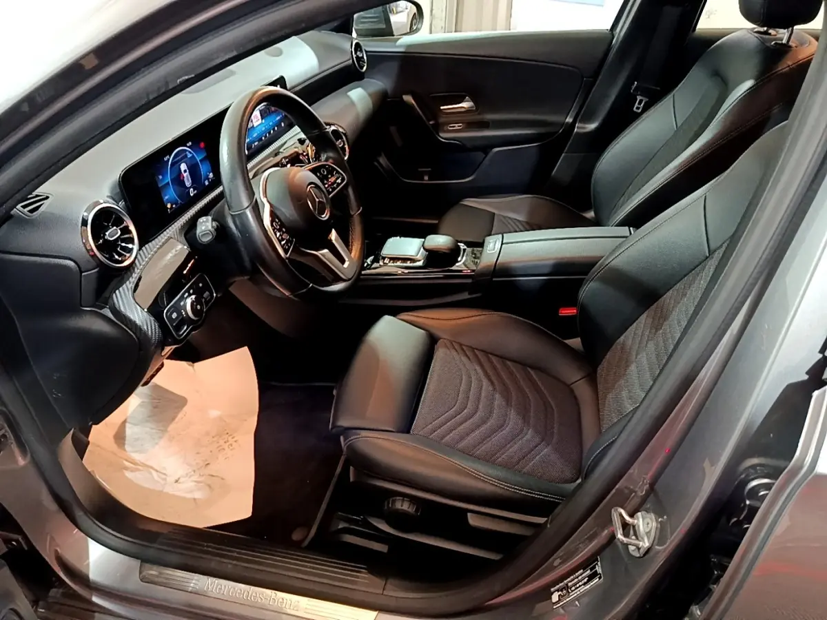Vue intérieure côté conducteur d'une Mercedes Classe A 180 d Business Line 2021 gris foncé avec volant cuir multifonctions et écran tactile.