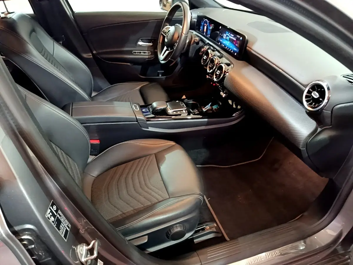 Vue intérieure côté conducteur d'une Mercedes Classe A 180 d Business Line 2021 avec sièges cuir noirs et tableau de bord digital.