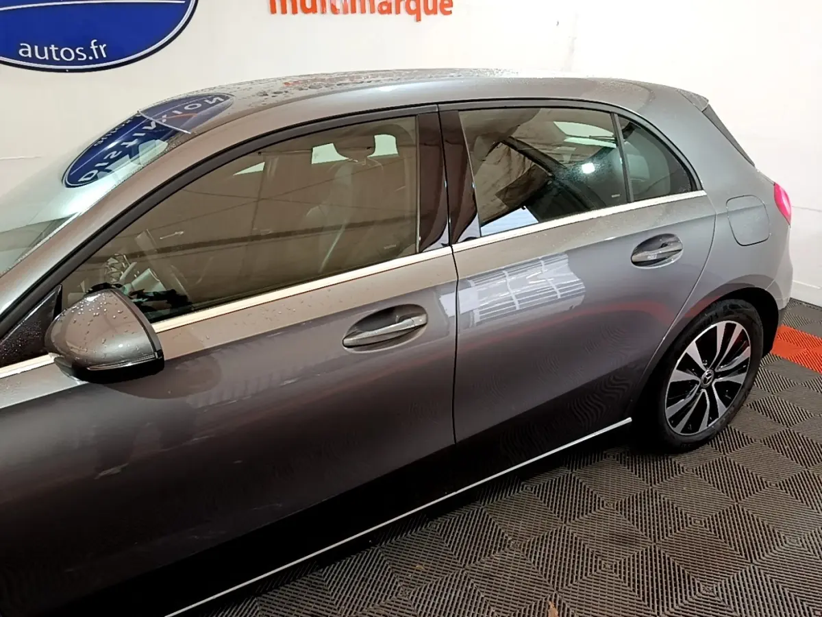 Vue côté gauche d'une Mercedes Classe A gris foncé, mettant en valeur les jantes alliage et les poignées de porte.