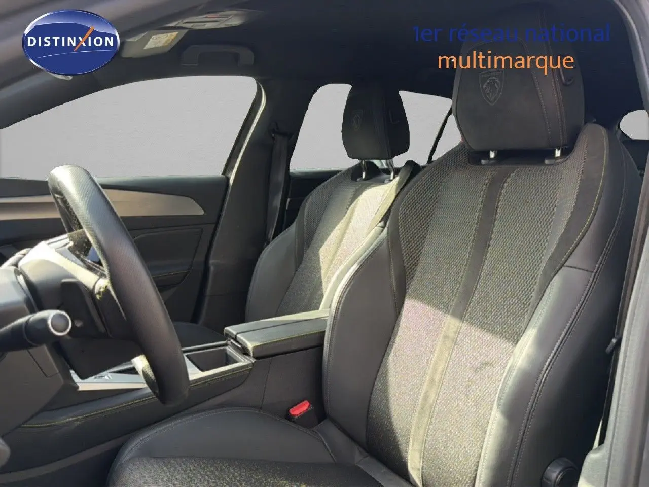 Vue intérieure côté gauche du Peugeot 408 1.2 HYBRID 145CH GT, sièges en tissu gris et cuir avec logo Peugeot brodé.