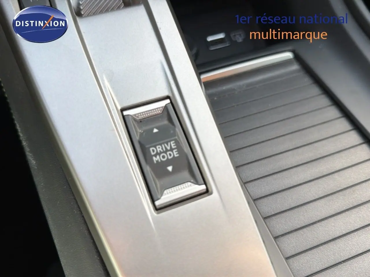 Gros plan sur le bouton Drive Mode dans la console centrale argentée d'une Peugeot 408 gris selenium metal 2025.