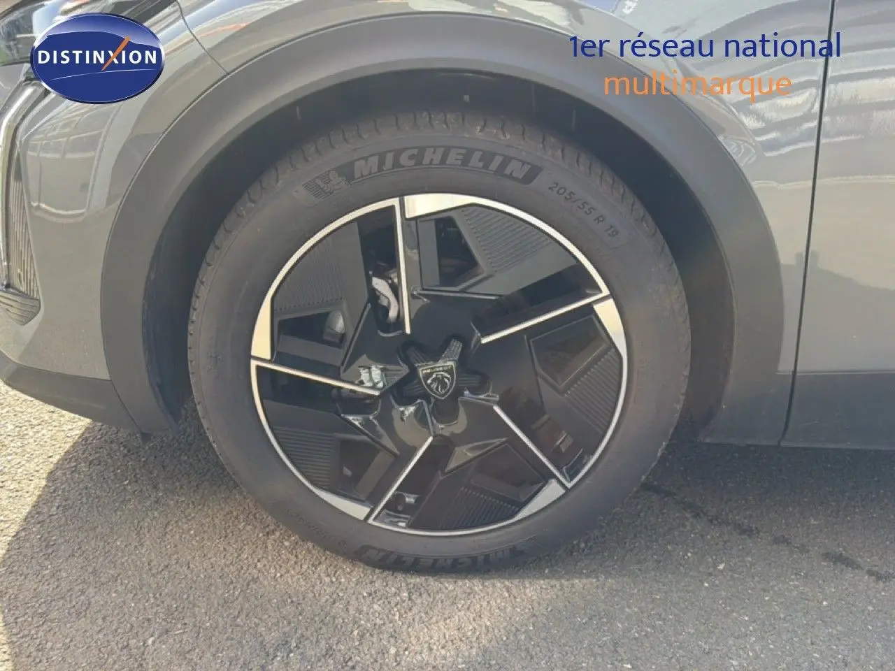 Gros plan sur la roue avant gauche d'une Peugeot 408 gris selenium metal, jante noire et argentée au design moderne.