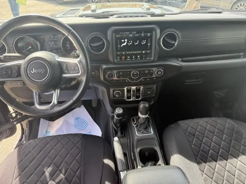 Vue intérieure avant du Jeep Wrangler Unlimited 2022 noir, montrant le volant, la console centrale et l'écran tactile.