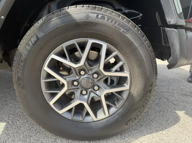 Gros plan sur la roue avant droite du Jeep Wrangler Unlimited noir, mettant en valeur la jante alliage et le pneu Michelin Latitude.
