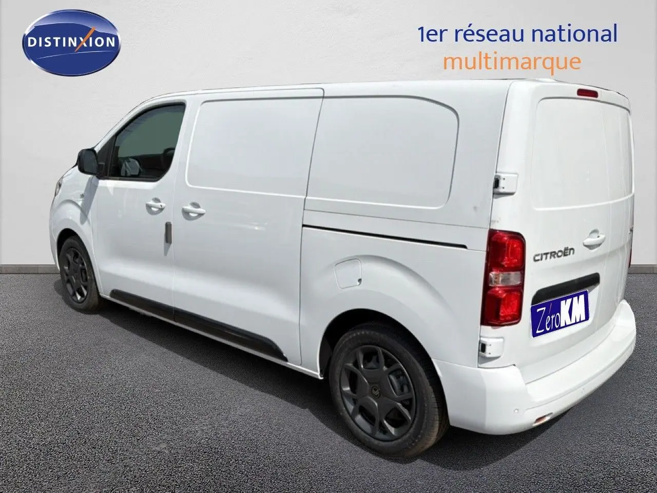 Vue 3/4 arrière droite d’un Citroën Jumpy blanc Kaolin avec jantes noires et porte latérale coulissante fermée.