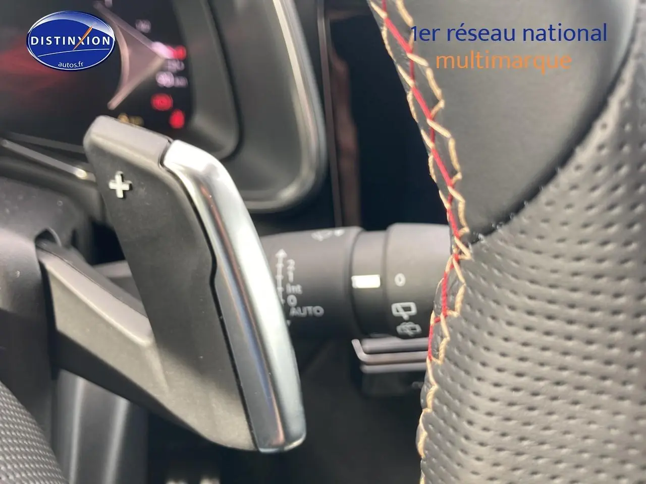 Gros plan sur la palette de changement de vitesse au volant en cuir perforé avec surpiqûres rouges du DS7 Crystal Pearl.