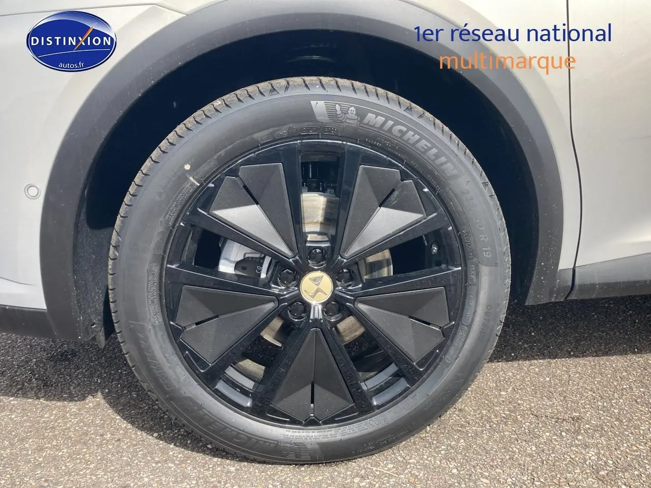 Gros plan sur la jante noire à design géométrique du DS7 Crystal Pearl côté gauche, avec pneu Michelin visible.