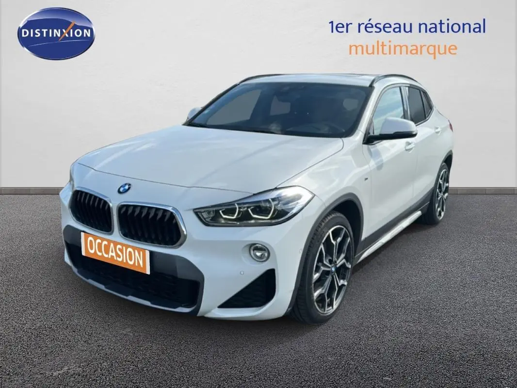 BMW X2 blanc vue 3/4 avant droit avec jantes alliage 19 pouces et toit ouvrant panoramique visible.