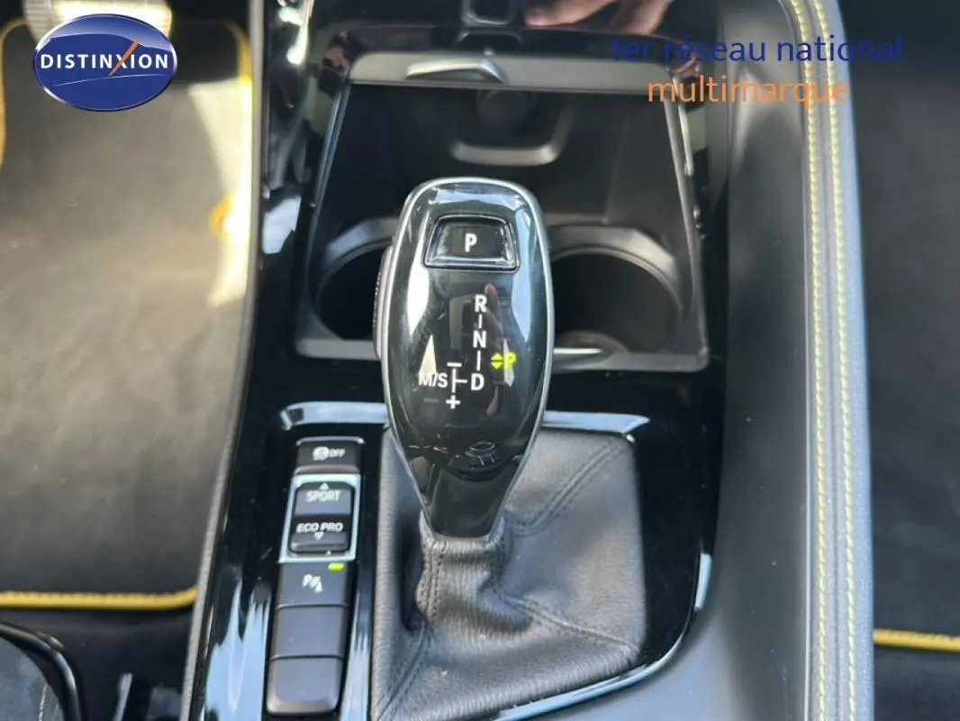 Le levier de vitesses automatique noir de la BMW X2 M Sport X 2018, avec console et surpiqûres jaunes visibles.