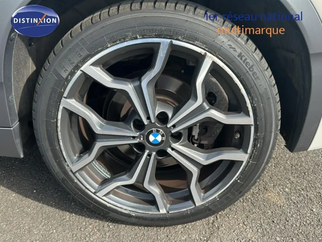 Gros plan sur la jante alliage 19 pouces gris foncé du BMW X2 blanc, mettant en valeur le logo central BMW.