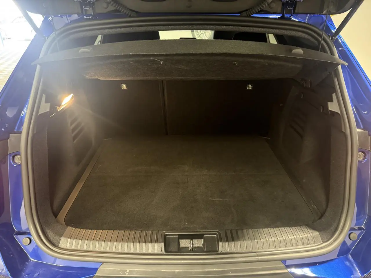 Coffre ouvert vu de l'arrière d'une Renault Symbioz bleu, montrant un espace de chargement spacieux et éclairé.