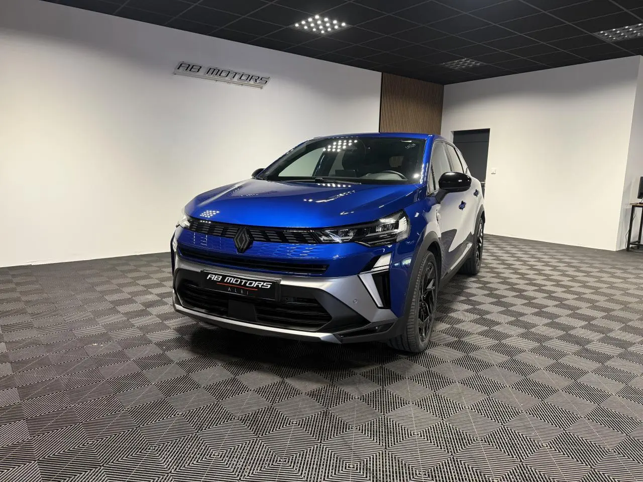 Vue 3/4 avant d’un Renault Symbioz bleu Iron avec calandre noire et jantes noires dans un showroom.