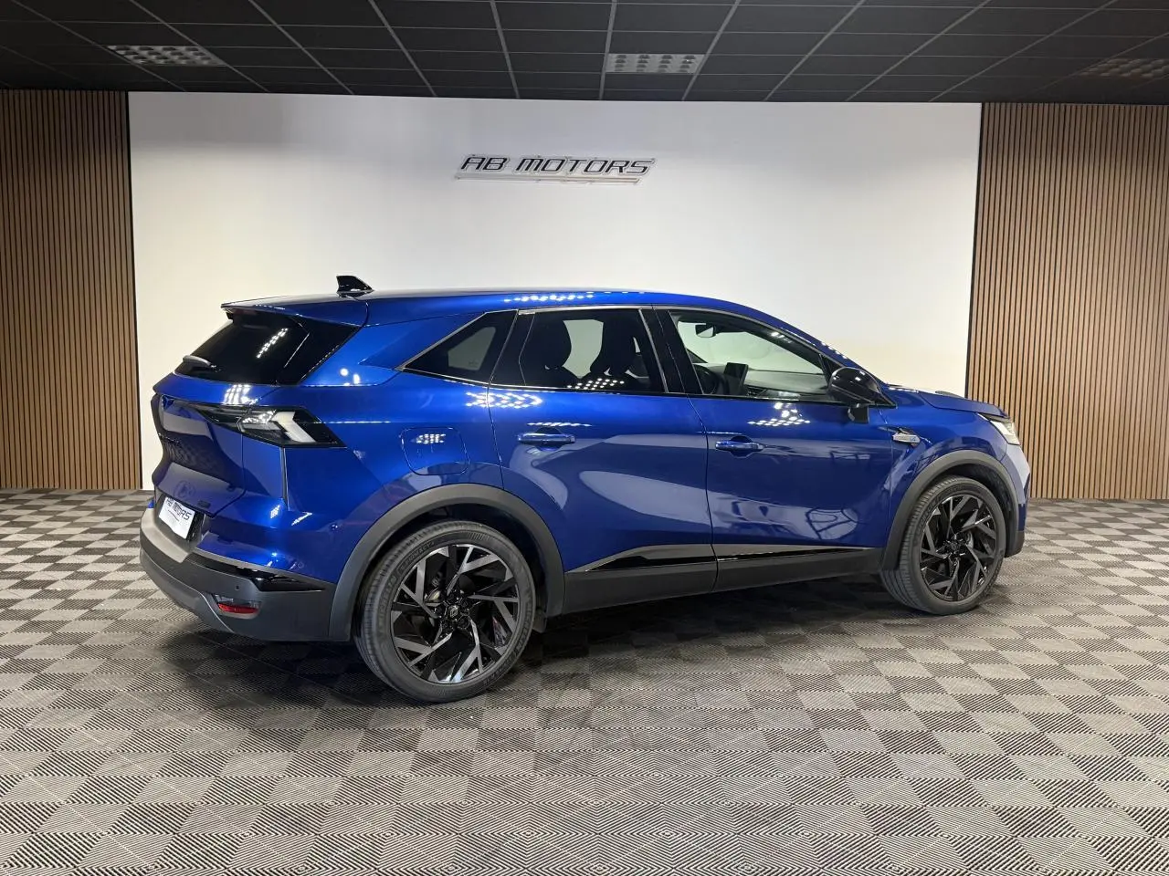Renault Symbioz bleu Iron en vue profil droit, avec jantes noires et détails noirs brillants sur carrosserie.