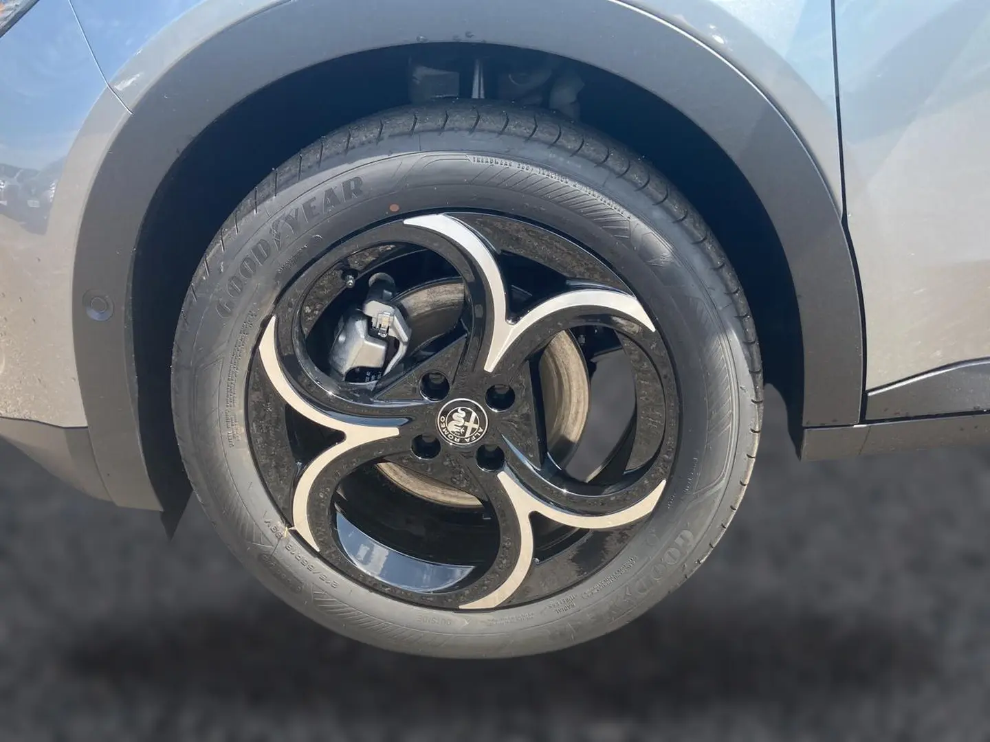 Gros plan sur la roue avant droite grise d'une Alfa Romeo Junior 1.2 hybride avec jante alliage noire et argentée au design distinctif.