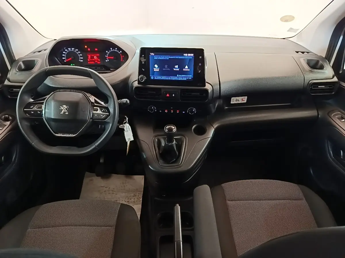Vue intérieure avant du Peugeot Partner 2020, tableau de bord noir avec écran tactile et volant multifonction.