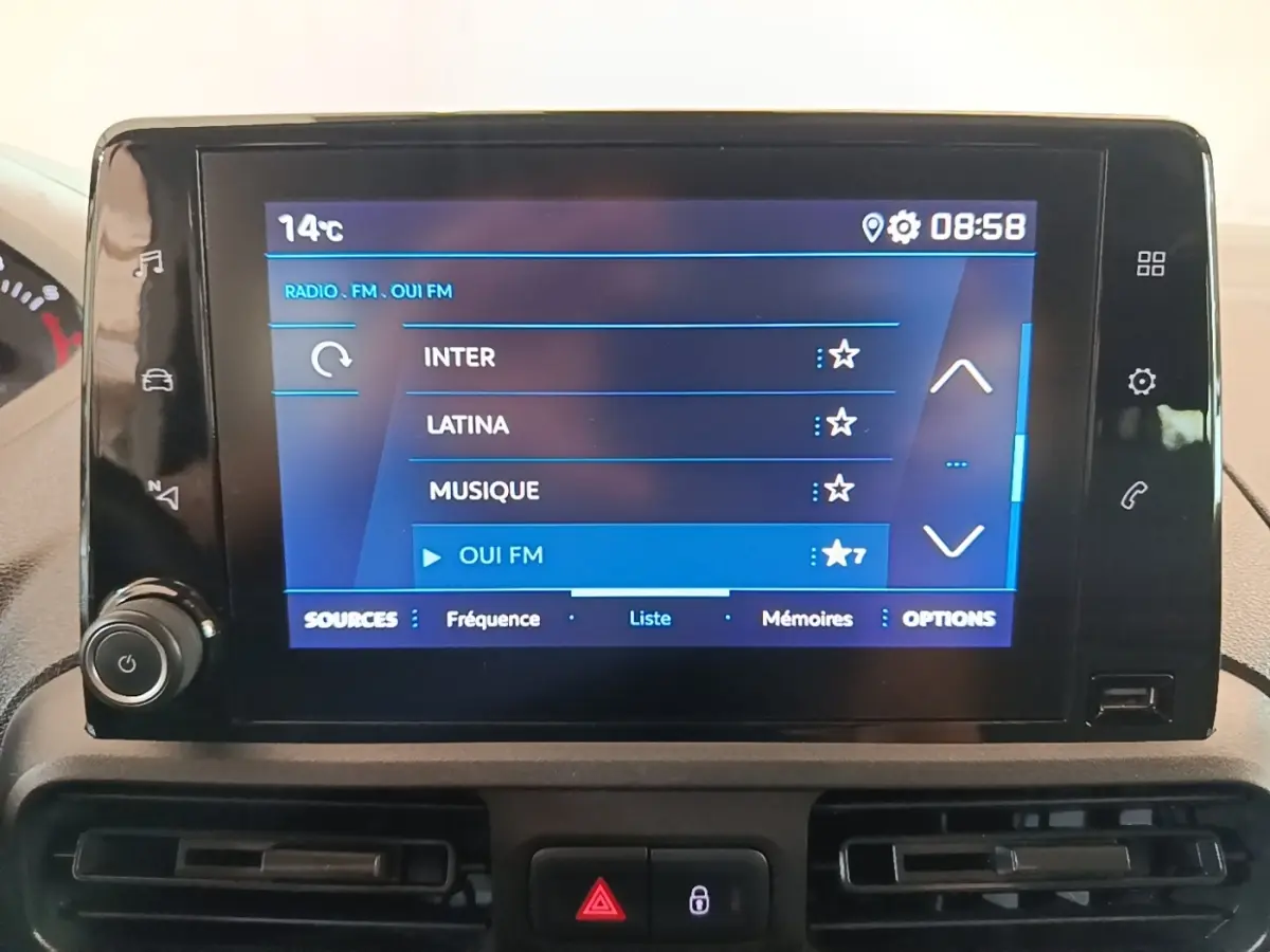 Écran tactile central du tableau de bord du Peugeot Partner 2020 affichant les stations radio FM, avec commandes autour.