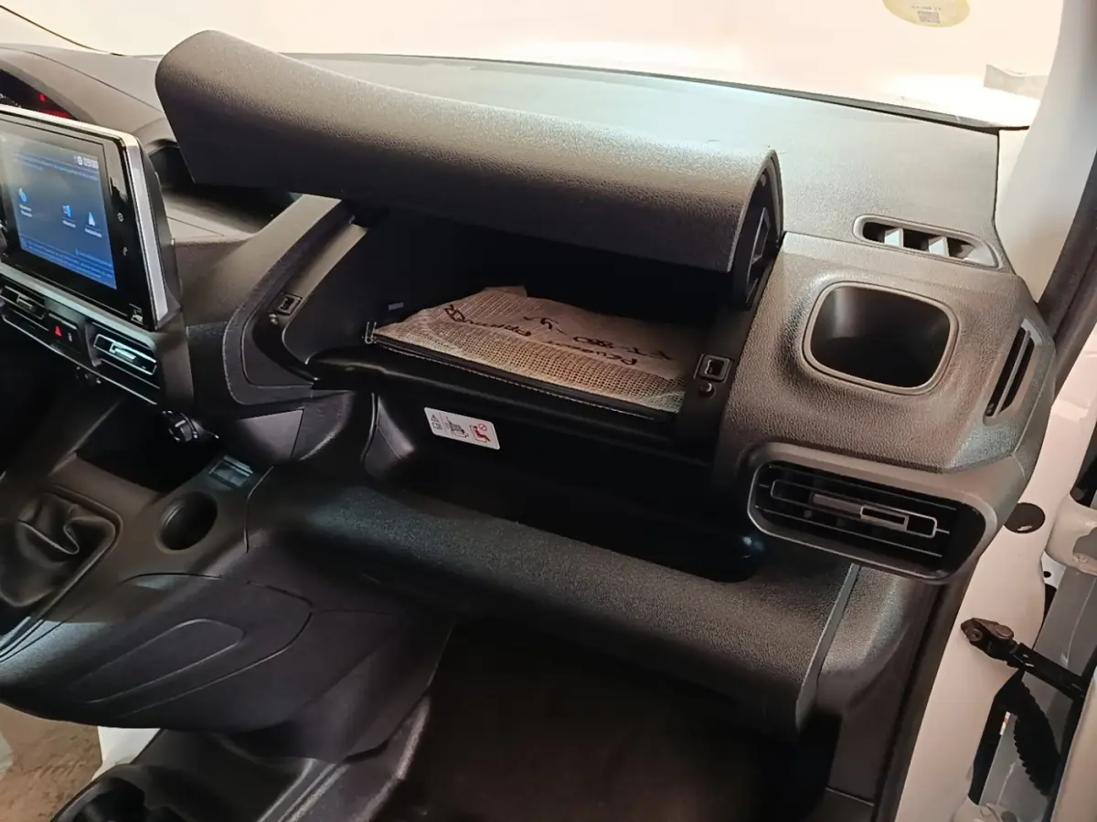 Intérieur du Peugeot Partner 2020, vue côté passager sur la boîte à gants ouverte et la console centrale noire.